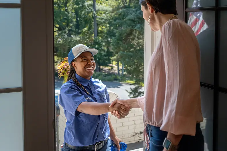 Person in a blue shirt shaking hands with someone indoors near an open door 1